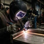 Male welder wearing a protective helmet welding a strong metal joint without undercut defects.